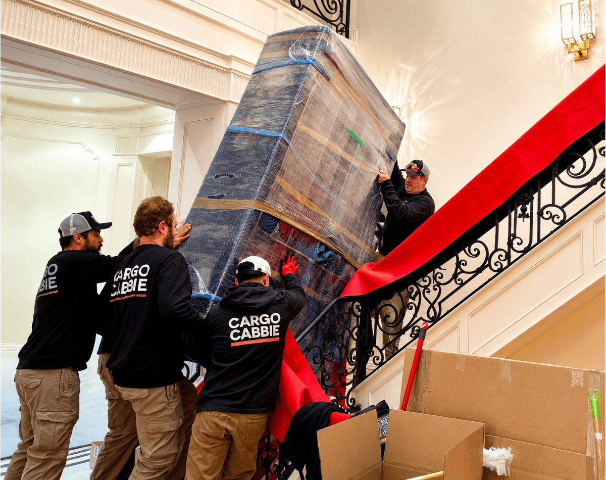 CARGO CABBIE white glove movers carrying a wrapped mattress up a grand staircase during a Toronto home move